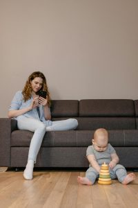Kodėl telefonų priedai tapo nepakeičiami žmonėms, auginantiems mažus vaikus Tėvai naudoja išmanųjį telefoną su apsauginiais priedais namų aplinkoje su vaiku