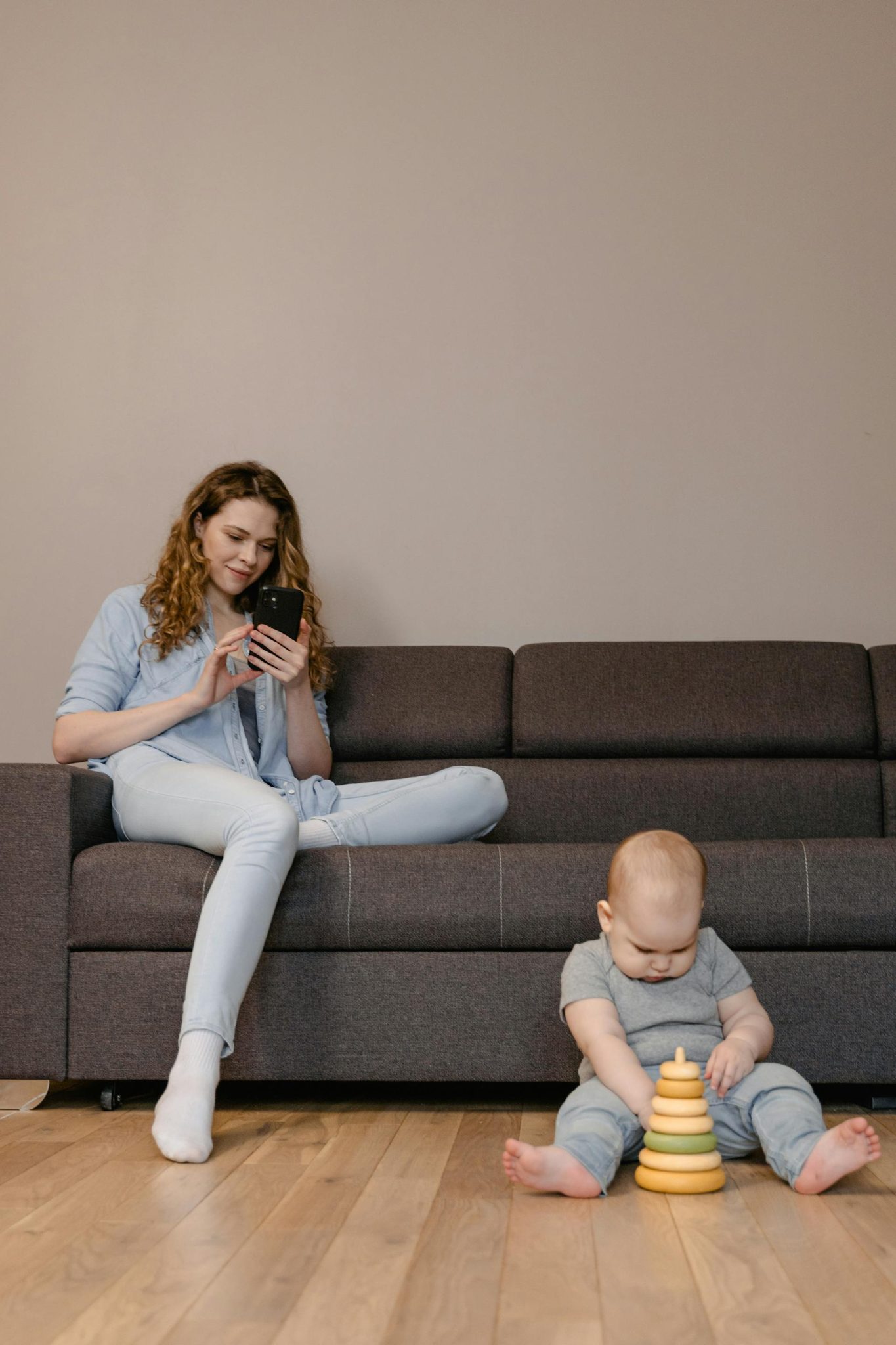 Tėvai naudoja išmanųjį telefoną su apsauginiais priedais namų aplinkoje su vaiku